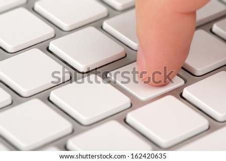 Close-up index finger is pressing an empty computer keyboard key with bokeh effect