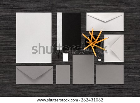 Template for corporate branding identity. Mockup consist of paper, envelopes, business card, notebook, pencils, eraser, binder clip. For design presentations or portfolio. Top view on black table.