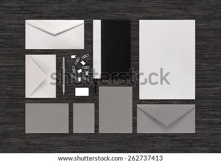 Top view of branding identity mock-up with templates for design presentation or portfolio on black table. Consists of envelopes, paper, notebook, pen, eraser, clips, business card.