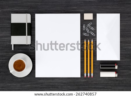 Branding identity mock up with templates for design presentation or portfolio on black table. Includes envelopes, paper, notebook, pencils, eraser, clips, lighter, cup of coffee.