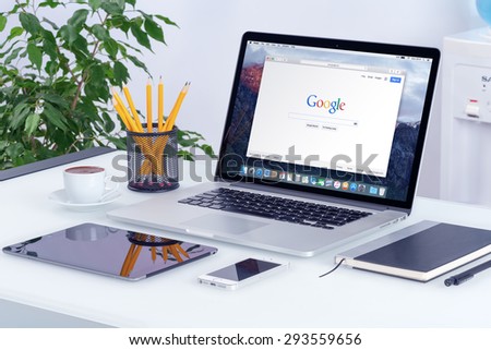 Apple 15 inch MacBook Pro Retina with an open tab in Safari browser which shows Google search web page with iPad and iPhone on the office desk workplace. Varna, Bulgaria - May 29, 2015.