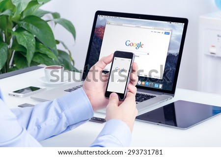 Google search on Apple iPhone screen and Macbook Pro Retina display that is on office desk. Multi devices multitasking concept. All gadgets in full focus. Varna, Bulgaria - May 29, 2015.