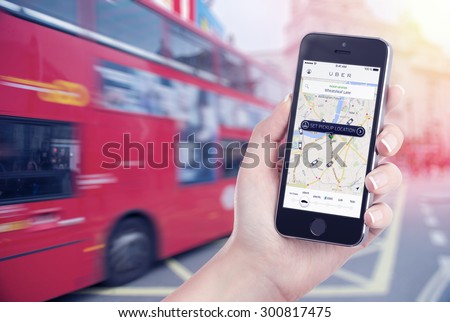 Car search through the Uber app that is displayed on the Apple iPhone screen in female hand. Blurred street view with bus and flare sun light on the background. Varna, Bulgaria - May 26, 2015.