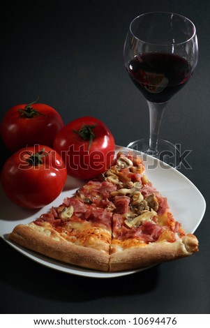 Pizza with tomatoes a glass wine on a black background.