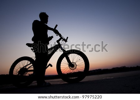 cyclist listen music on city background at the sunset