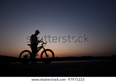 cyclist listen music on city background at the sunset