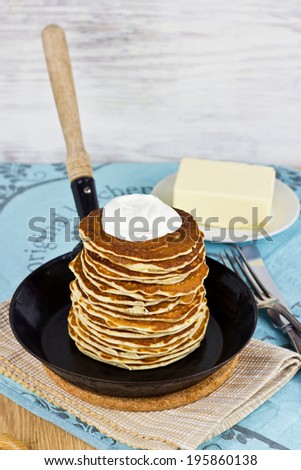 Old frying pan with pancakes and sour cream