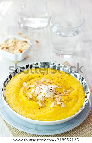 Carrot soup with sour cream and almond petals (selective focus)