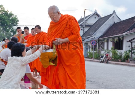 LUANG PRABANG, LAO - MAY 12: Every day very early in the morning, the monks walk the streets to beg give food offerings to a Buddhist monk on May 12, 2014 in Luang Prabang, Laos.