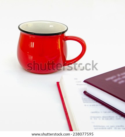 red cup of coffee and two books on white background