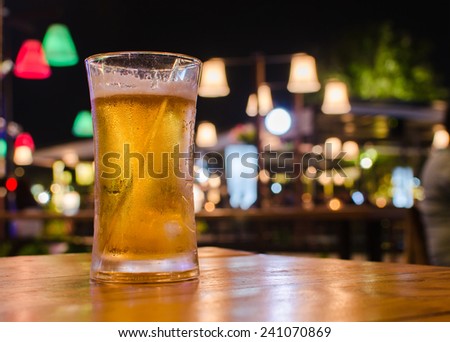 Glass of beer with bar scene in the background