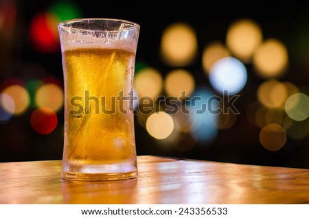 Glass of beer with bokeh bar scene in the background