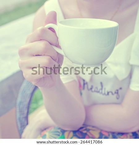 woman holding white coffee cup, vintage tone