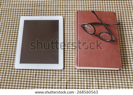 vintage tone with old book, smart-phone and glasses on table.