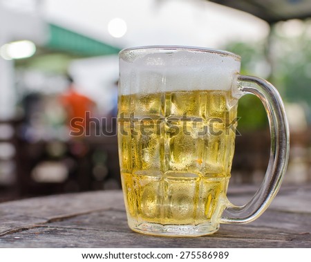Glass of beer with bar scene in the background