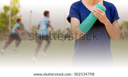 broken arm with green cast on blurred background kid soccer player in academy - insurance concept
