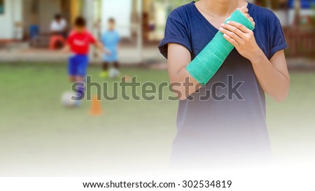 broken arm with green cast on blurred background kid soccer player in academy - insurance concept
