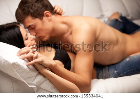 young lovers kissing on the couch. focused on hand