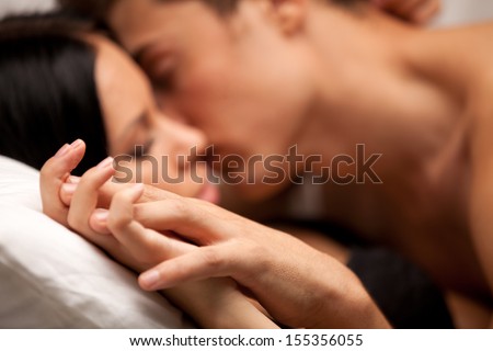 Young Lovers Kissing On The Couch. Focused On Hand