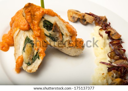 Chicken roll stuffed with spinach and melted cheese. Mashed potatoes with mushrooms chili at the side. Isolated on white. Close up