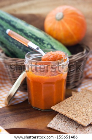 Squash caviar in a glass jar on the wooden board with bread crisps
