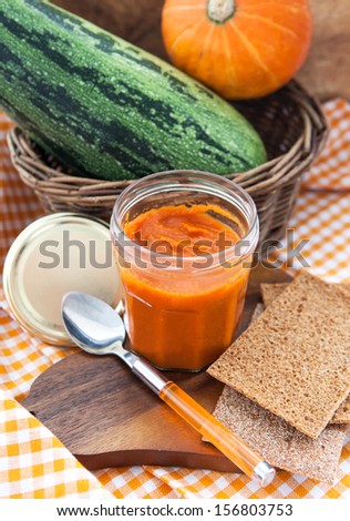 Squash caviar in a glass jar on the wooden board with bread crisps