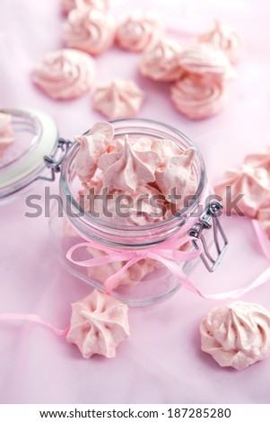 Pink meringues in a glass jar on pastel background
