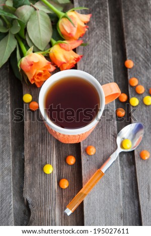 Cup of fresh black tea and colorful candies on the wooden table