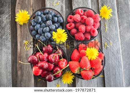 Fresh cherry, strawberry, blueberry and raspberry in a bowls on wooden table