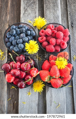 Fresh cherry, strawberry, blueberry and raspberry in a bowls on wooden table