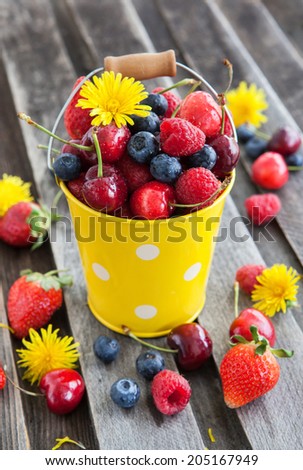 Fresh cherry, strawberry, blueberry and raspberry in a bucket on wooden table