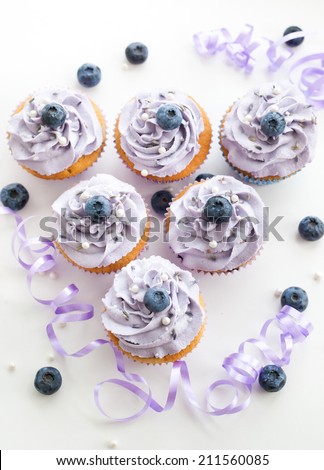 Tasty blueberry and lavender cupcakes on white background