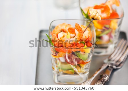 Shrimp, avocado, tomato, salmon and red caviar cocktail salad served in a glass