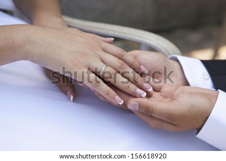 groom holds the bride\'s hands with wedding ring