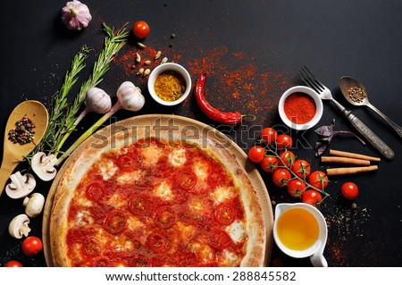 Pizza margarita with tomato and cheese and ingredients spices pepper tomato oil basis for pizza on a black background