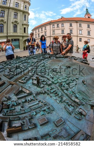 LJUBLJANA, SLOVENIA - AUGUST 24th 2014: Tourists looking at the model of the Ljubljana city center on Preseren square on a summer afternoon.