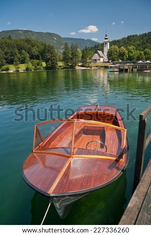 Electric boat in Bohinj lake tied by the pier in front of the church, Slovenia