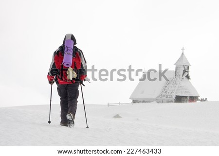 Lone hiker going to the church of Snowy Mary on Velika planina in a wind blowing snow, Slovenia