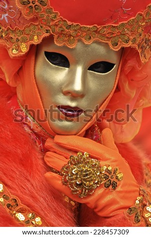 Orange Venice carnival mask with a gold face posing