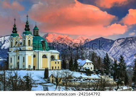 St. Ana baroque church in the morning with Kamnik-Savinja Alps and clouds lit by the rising sun