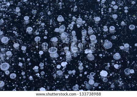 Layer of dark blue ice sheet with bubbles of air. Abstract cosmic background.