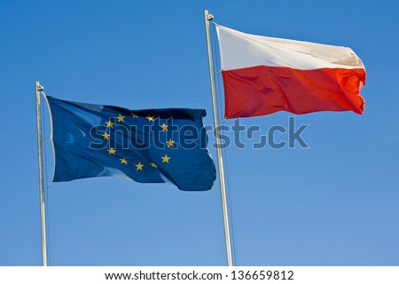 European Union flag and a Polish flag on a background of clear sky