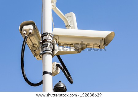 Security cameras on a pole set to the observations the street and people.