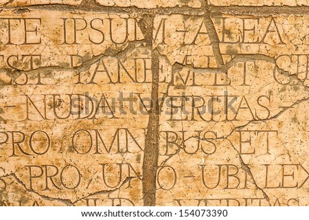 Cracked wall with Latin inscriptions and Roman letters, marble background.