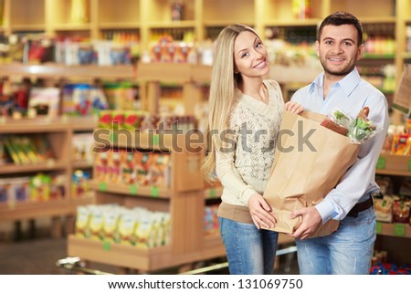 Young couple with package of products in store