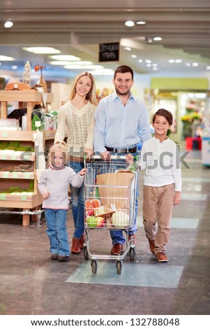 Family with children products with a cart in the store