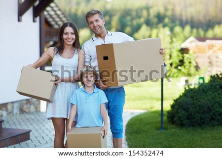Smiling family with boxes by the house