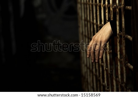 Human hand through a prison cell in the conclusion