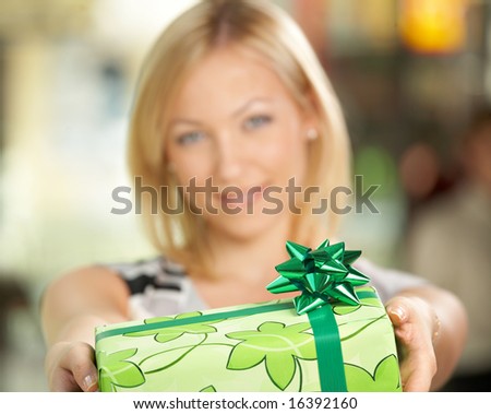 The attractive girl smiles and gives a gift in packing