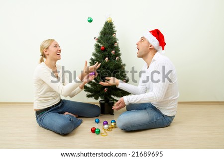 The pair juggles with spheres sitting at a Christmas pine